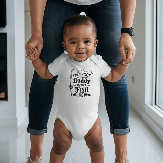 Baby wearing white Gerber Onesies® with "I'm Proof Daddy Doesn't Fish All The Time" print, held by adult hands
