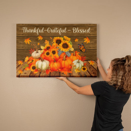 Thankful Grateful and Blessed canvas wall art with autumn pumpkins, sunflowers, and butterflies on wooden background