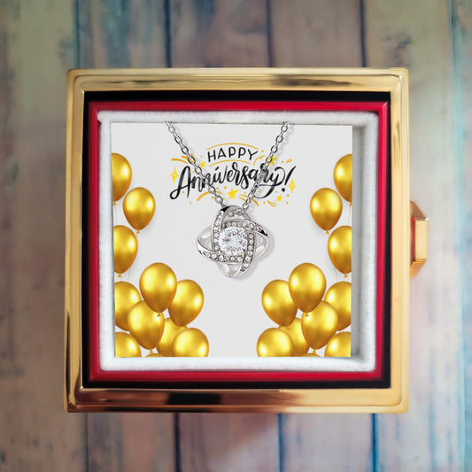 Happy Anniversary Love Knot Necklace with cubic zirconia in luxury gift box with preserved rose and gold balloons background
